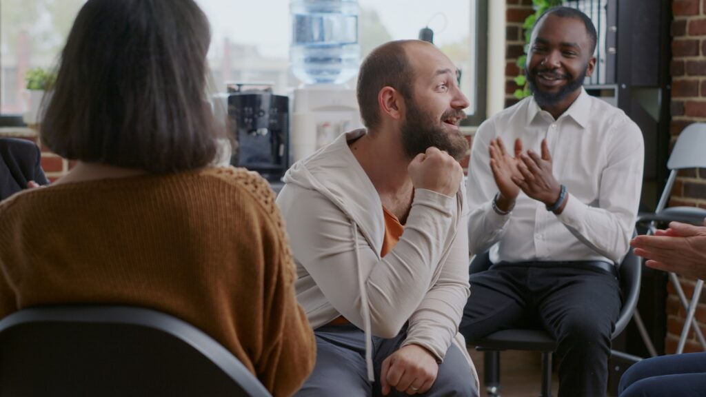 Man doing handshake with people after sharing progress and success at aa group meeting